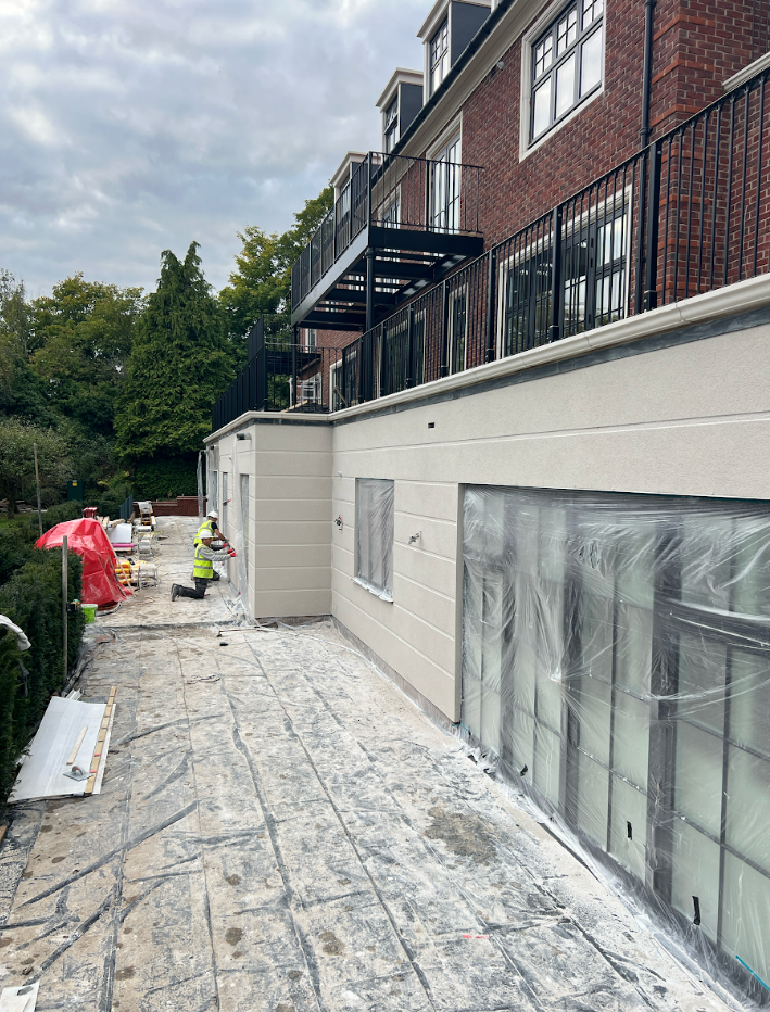 Experienced contractor applying monocouche rendering in Surrey using a spray pump.